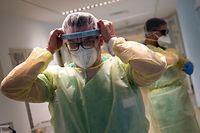 Senior doctor Thomas Marx puts on his personel protective gear before he enters the room of a patient infected with the novel coronavirus Covid-19 in an intensive care unit at the hospital in Freising, southern Germany on April 12, 2021. (Photo by LENNART PREISS / AFP)