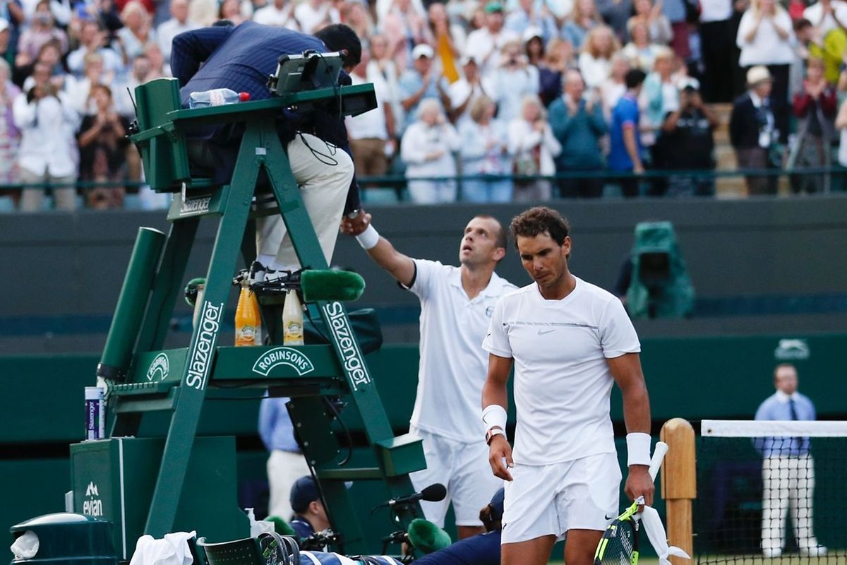 Spain's Rafael Nadal (R) returns to his chair as Luxembourg's Gilles Muller (L) shakes hands with the umpire after Muller won their men's singles fourth round match on the seventh day of the 2017 Wimbledon Championships at The All England Lawn Tennis Club in Wimbledon, southwest London, on July 10, 2017.
Muller won 6-3, 6-4, 3-6, 4-6, 15-13. / AFP PHOTO / Adrian DENNIS / RESTRICTED TO EDITORIAL USE