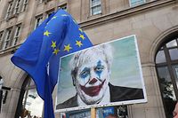 19.10.2019, Großbritannien, London: Ein Demonstrant trägt ein Plakat, auf dem der britische Premierminister Johnson als Comicfigur "Der Joker" abgebildet ist, während eines Protestmarschs unter dem Titel "Let Us Be Heard". Das britische Parlament ist am Samstagvormittag zu einer historischen Sondersitzung zusammengekommen, um über das zwischen London und Brüssel vereinbarten Brexit-Abkommen abzustimmen. Der britische Premierminister Johnson verfügt über keine Mehrheit im Unterhaus; er muss um jede Stimme kämpfen. Foto: Andrew Matthews/PA Wire/dpa +++ dpa-Bildfunk +++