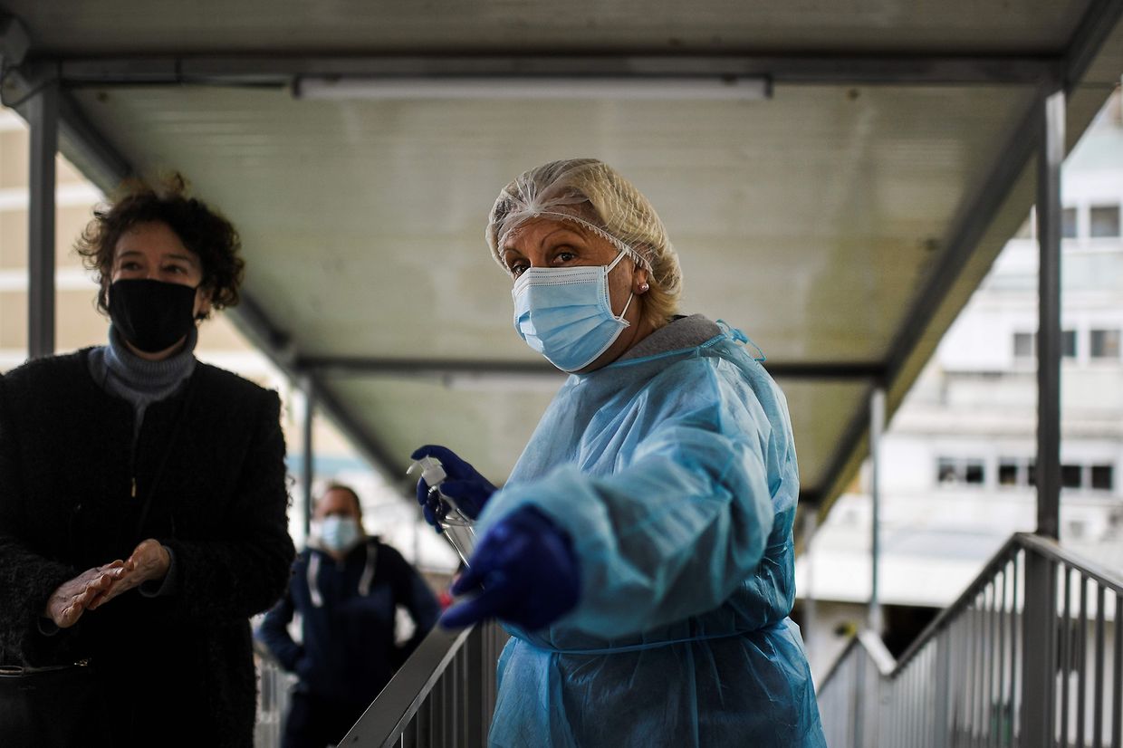 Uma mulher dispõe de desinfetante de mãos numa escola em Benfica, Lisboa, aos eleitores.  