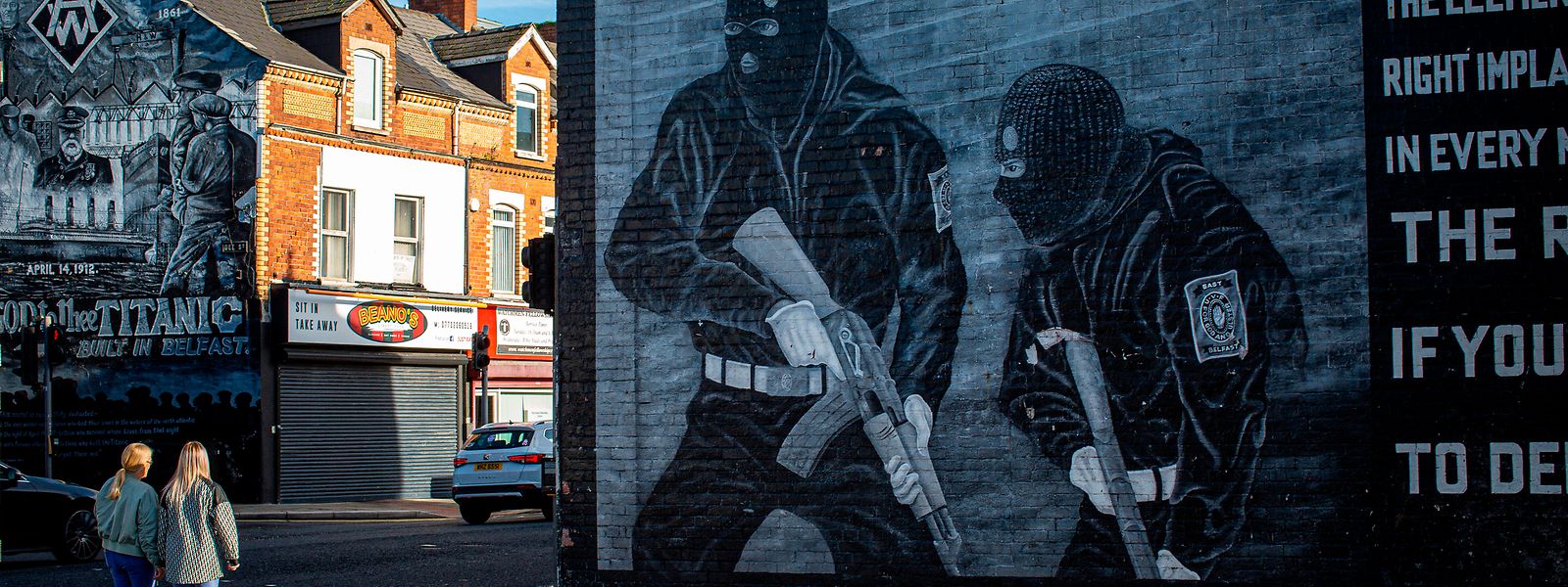 Zwei junge Frauen gehen in der Newtownards Road in East Belfast an einem Wandgemälde der pro-britischen loyalistischen Paramilitärs vorbei.