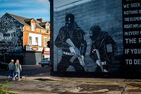 Two young woman walking past a Loyalist paramilitary mural on the Newtownards road on the 8th  November 2021 in Belfast,Northern Irland .