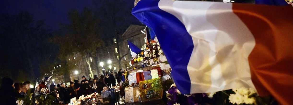 TOPSHOTS
A French flag flutters over candles and flowers as people gather at Place de la Republique (Republic Square) in Paris on November 22, 2015 to pay tribute for the victims of the November 13 terror attacks. A coordinated wave of attacks on Parisian nightspots claimed by Islamic State group (IS) jihadists killed 130 people. AFP PHOTO / LOIC VENANCE