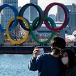 A couple pose for photos in front of the Olympic rings on display at the Odaiba waterfront in Tokyo on February 24, 2021. (Photo by Philip FONG / AFP)