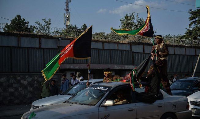 People carry the Afghanistan's national flag on the occasion of 102th Independence Day of the country in Kabul, amid the Taliban's military takeover 