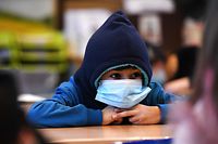 A boy wears a hat and a face mask as he attends lessons in his aerated classroom at the Petri primary school in Dortmund, western Germany, on November 23, 2021 amid the novel coronavirus / COVID-19 pandemic. (Photo by Ina FASSBENDER / AFP)
