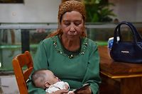 (FILES) This file photo taken on May 31, 2019 shows a Uighur woman holding a baby in a Uighur restaurant in Hotan in China's northwest Xinjiang region. - Chinese authorities are carrying out forced sterilisations of women in an apparent campaign to curb the growth of ethnic minority populations in the western Xinjiang region, according to research published on June 29, 2020. (Photo by GREG BAKER / AFP)