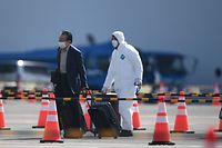 A passenger (L) disembarks from the Diamond Princess cruise ship - in quarantine due to fears of the new COVID-19 coronavirus - at the Daikoku Pier Cruise Terminal in Yokohama on February 19, 2020. - Relieved passengers began leaving a coronavirus-wracked cruise ship in Japan on February 19 after testing negative for the disease that has now claimed more than 2,000 lives in China. (Photo by CHARLY TRIBALLEAU / AFP)