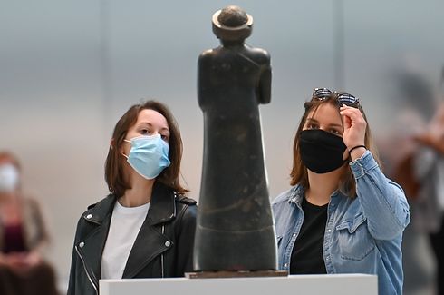 Visitors wearing face masks look at a piece displayed at the Louvre Lens museum reopened to the public on June 3, 2020 as France easing of lockdown measures taken to curb the spread of the COVID-19 pandemic, caused by the novel coronavirus. (Photo by DENIS CHARLET / AFP)