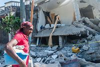 A Haitian woman cries as she passes a  destroyed house in Les Cayes on August 15, 2021, after a 7.2-magnitude earthquake struck the southwest peninsula of the country. - Hunched on benches, curled up in chairs or even lying the floor, those injured in the powerful earthquake that wreaked havoc on Haiti on Saturday crowded an overburdened hospital near the epicenter. The emergency room in Les Cayes, in southwestern Haiti, which was devastated by the 7.2-magnitude quake on Saturday morning that killed at least 724 people, is expecting reinforcements to help treat some of the thousands of injured. (Photo by Reginald LOUISSAINT JR / AFP)