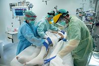 Nurses and doctor tend to a  patient inside the negative pressure room  during the night shift of April 10 to 11, 2020, in the intensive care unit exclusively for COVID-19 patients at the Ixelles Hospital in Brussels, amid the COVID-19 pandemic, caused by the novel coronavirus. (Photo by Aris Oikonomou / AFP)