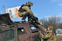 TOPSHOT - An Ukrainian Territorial Defence fighter takes the automatic grenade launcher from a destroyed Russian infantry mobility vehicle GAZ Tigr after the fight in Kharkiv on February 27, 2022. - Ukrainian forces secured full control of Kharkiv on February 27, 2022 following street fighting with Russian troops in the country's second biggest city, the local governor said. (Photo by Sergey BOBOK / AFP)