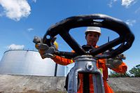 A PT Pertamina worker opens a gauge near crude oil tanks on Bunyu island, Indonesia's East Kalimantan province in this February 8, 2011 file photo. Brent crude oil futures rose to a 2-1/2 year high over $105 a barrel a barrel on February 21, 2011 and U.S. prices rallied by over $3 as clashes in Libya threatened to disrupt oil flows from the OPEC member. REUTERS/Beawiharta/Files (INDONESIA - Tags: ENERGY BUSINESS CIVIL UNREST)