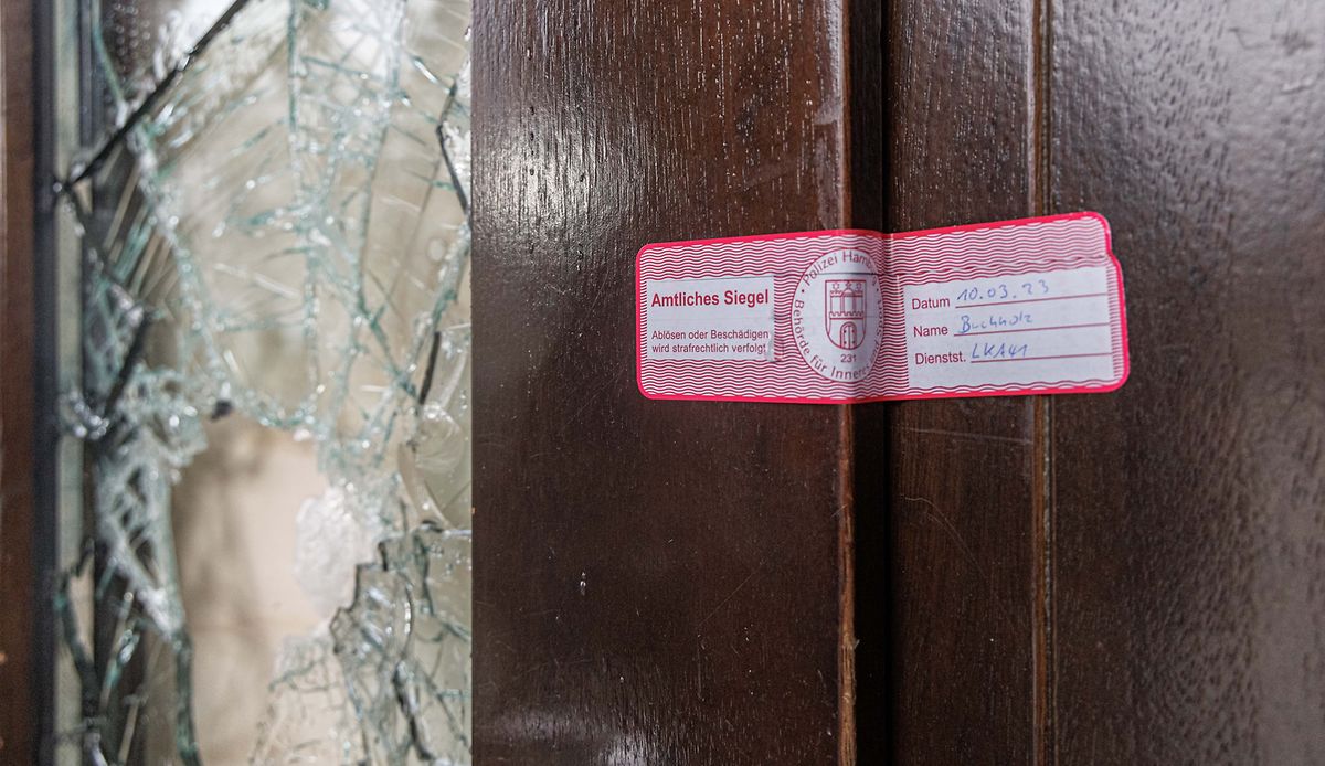 Ein Siegel der Polizei klebt am Eingang zum Gebäude der Zeugen Jehovas neben einer beschädigten Glasscheibe. 