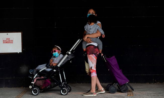 A woman waits with her children at a food distribution centre in Spain last year