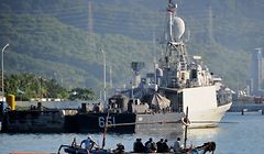 An outrigger canoe sails past an Indonesian Navy ship at the naval base in Banyuwangi, East Java province, on April 24, 2021, as the military continues search operations off the coast of Bali for the Navy's KRI Nanggala submarine that went missing April 21 during a training exercise. (Photo by SONNY TUMBELAKA / AFP)