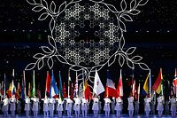 TOPSHOT - the Olympic flame is extinguished as volunteers hold the flags of participating countries during the closing ceremony of the Beijing 2022 Winter Olympic Games, at the National Stadium, known as the Bird's Nest, in Beijing, on February 20, 2022. (Photo by Anne-Christine POUJOULAT / AFP)