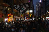 A man waves a flag that reads in Chinese "liberate Hong Kong revolution of our times" as people raise their phone lights during a pro-democracy rally in Wan Chai in Hong Kong on December 8, 2019. - Hong Kong democracy protesters are hoping for huge crowds December 8 at a rally they have billed as a "last chance" for the city's pro-Beijing leaders in a major test for the six-month-old movement. (Photo by Alastair Pike / AFP)
