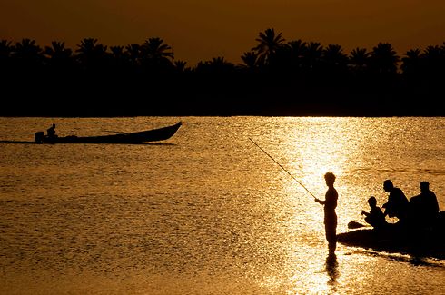 TOPSHOT - Iraqis fish at the Shatt al-Arab river, formed by the confluence of the Euphrates and the Tigris, near Basra in southern Iraq, on April 28, 2020 during the Muslim holy month of Ramadan. (Photo by Hussein FALEH / AFP)