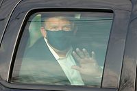 TOPSHOT - US President Trump waves from the back of a car in a motorcade outside of Walter Reed Medical Center in Bethesda, Maryland on October 4, 2020. (Photo by ALEX EDELMAN / AFP)