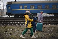 TOPSHOT - A family crosses the railway trucks at Lviv train station, western Ukraine, on March 5, 2022. - The UN Human Rights Council on March 4, 2022, overwhelmingly voted to create a top-level investigation into violations committed following Russia's invasion of Ukraine. More than 1.2 million people have fled Ukraine into neighbouring countries since Russia launched its full-scale invasion on February 24, United Nations figures showed on March 4, 2022. (Photo by Daniel LEAL / AFP)