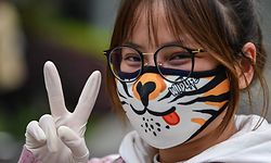 A woman wearing a face mask gestures on a street in Wuhan, China's central Hubei province on April 3, 2020. - Wuhan, the central Chinese city where the coronavirus first emerged last year, partly reopened on March 28 after more than two months of near total isolation for its population of 11 million. (Photo by Hector RETAMAL / AFP)