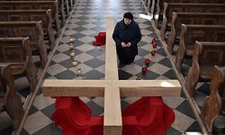 TOPSHOT - Catholic Christian believer kneels next to a giant cross during the Sunday service on April 5, 2020, in the town of Achmiany, some 130 km northwest of Minsk, during Palm Sunday celebrations which mark a week before Easter. (Photo by Sergei GAPON / AFP)