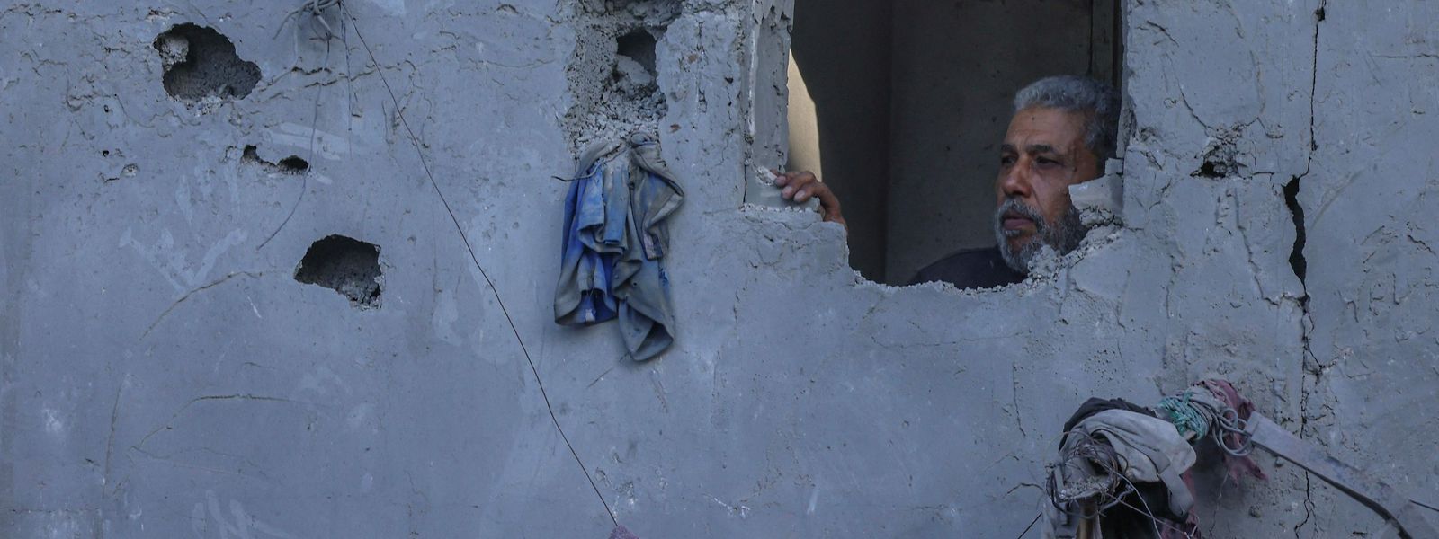 Um homem palestiniano inspeciona os danos na sua casa após um bombardeamento israelita em Rafah, no sul da Faixa de Gaza, em 18 de outubro de 2023, no meio de batalhas contínuas entre Israel e o Hamas.  
