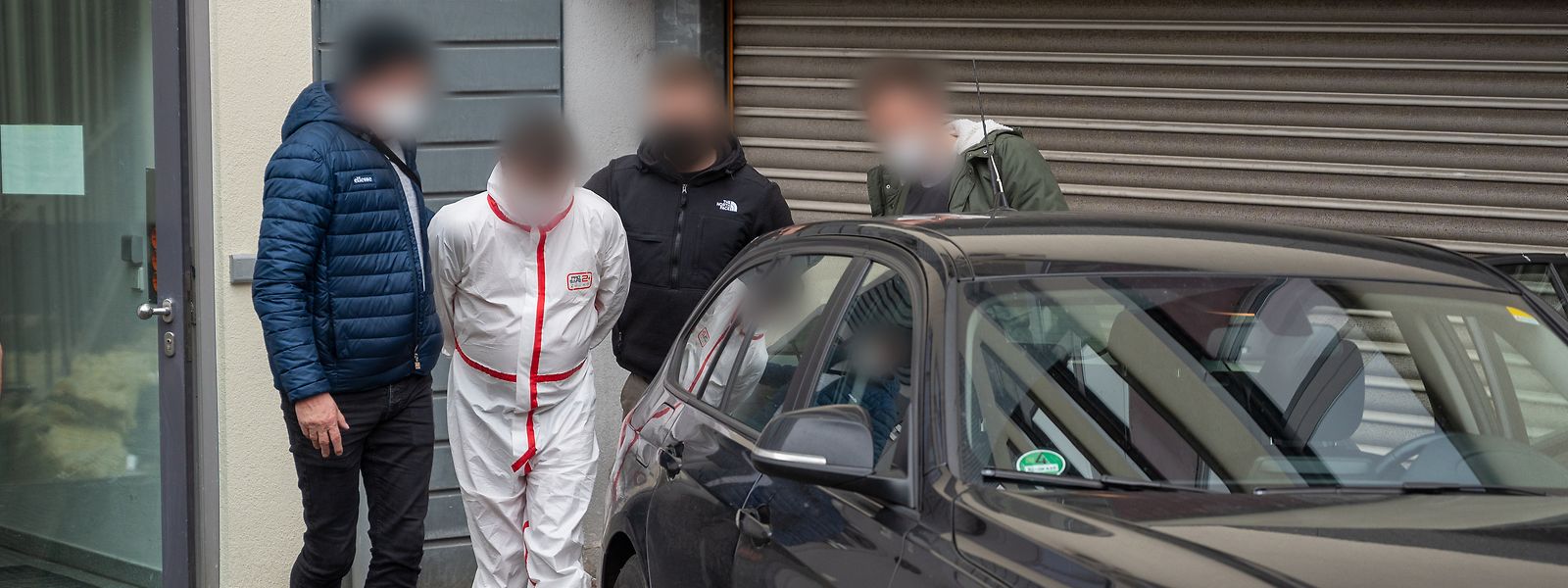 Polizisten bringen einen der Tatverdächtigen (im weißen Overall) kurz nach seine Festnahme aus dem Justizgebäude in Kaiserslautern. 