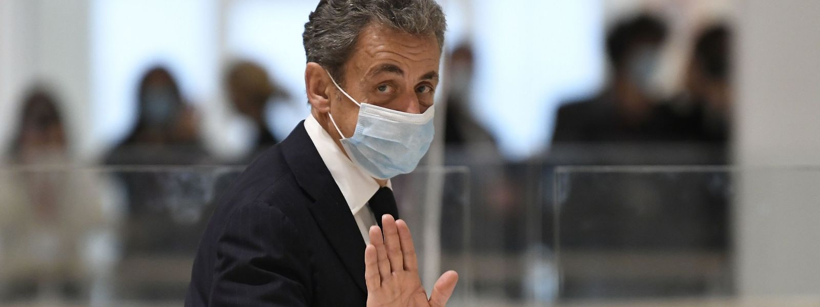 Auf dem Weg aus dem Gerichtssaal winkt der frühere Präsident Niclas Sarkozy den Fotografen zu.