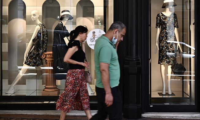 People in Genoa, Italy, walk past clothing shops on Monday, the day Italians were finally able to go outside without masks thanks to the whole country being declared a low-risk zone for coronavirus.