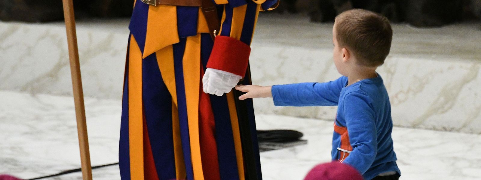 A boy who jumped from the audience onto the stage, interacts with a Swiss Guard as Cardinals look on during the weekly general audience on November 28, 2018 in Paul VI hall at the Vatican. (Photo by Vincenzo PINTO / AFP)