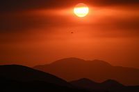 TOPSHOT - The sun sets behind wildfire smoke during the Fairview Fire near Hemet, California in Riverside County on September 7, 2022. - A ferocious heat wave scorching the western United States could finally begin to wane in the coming days, forecasters said on September 7, but they warned of dangerous fire conditions as howling winds sweep through the bone-dry region. (Photo by Patrick T. FALLON / AFP)