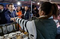 French President and liberal party La Republique en Marche (LREM) candidate for re-election Emmanuel Macron (L) meets people at an open market in Neuilly-sur-Seine, near Paris, on April 8, 2022, on his way out of an interview at French private radio station RTL, two days before the first round of the French presidential election. (Photo by Ludovic MARIN / AFP)