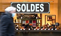 A pedestrian walks past an advertisement indicating discounts in a shoes shop, during the winter sales, in Rennes, northwestern France, on January 22, 2021. (Photo by Damien MEYER / AFP)