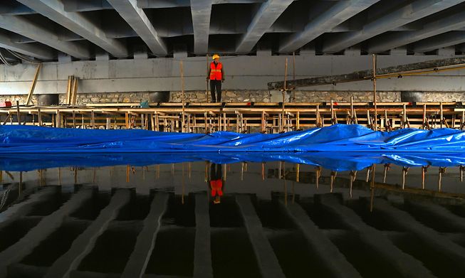 A worker is reflected on a creek at a construction site under a bridge in Beijing on Sunday
