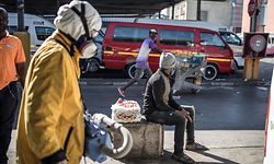 Steven Smith (L), a Scientology Volunteer Minister, carries his machine loaded with disinfectant as he walks through the Bree taxi rank in Newtown, Johannesburg, on May 7, 2020 during a sanitisation drive organised by the religious movement. (Photo by MARCO LONGARI / AFP)