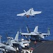 A US FA-18 hornet fighter jet flies past fighter jets and a E-2C Hawkeyes during a routine training aboard US aircraft carrier Theodore Roosevelt in the South China sea on April 10, 2018. 
The carrier group Theodore Roosevelt is transiting through the South China sea on its way to the Philippines from Singapore after participating in Operations Inherent Resolve (OIR) and Operation Freedom's Sentinel (OFS) in Syria, Iraq and Afghanistan. / AFP PHOTO / TED ALJIBE