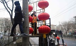 Two Chinese workers hang lanterns for the upcoming Lunar New Year along a street in Beijing on January 27, 2021. (Photo by WANG Zhao / AFP)