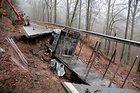 01.02.2021, Rheinland-Pfalz, Kordel: Ein Lastwagen wird bei Kordel (Kreis Trier-Saarburg) durch Stahlseile gesichert, nachdem sich in der Straße ein «kleiner Krater» gebildet hatte, in den der Lastwagen und ein Auto beim Befahren der Straße gerutscht sind. Zwei Personen sind verletzt ins Krankenhaus gebracht worden. Die Ursache sei noch unklar. Die Straße zwischen Kordel und dem Ortsteil Hochmark ist bis auf weiteres gesperrt. Foto: Harald Tittel/dpa +++ dpa-Bildfunk +++