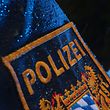 ARCHIV - 15.03.2019, Bayern, Kempten: ILLUSTRATION - Ein Polizist steht im Regen vor einem Streifenwagen, dessen Blaulicht aktiviert ist. Am Freitag beginnt am Landgericht München I der Prozess gegen zwei Männer, die ältere Menschen als falsche Polizeibeamte um ein Vermögen gebracht haben sollen. Foto: Karl-Josef Hildenbrand/dpa +++ dpa-Bildfunk +++