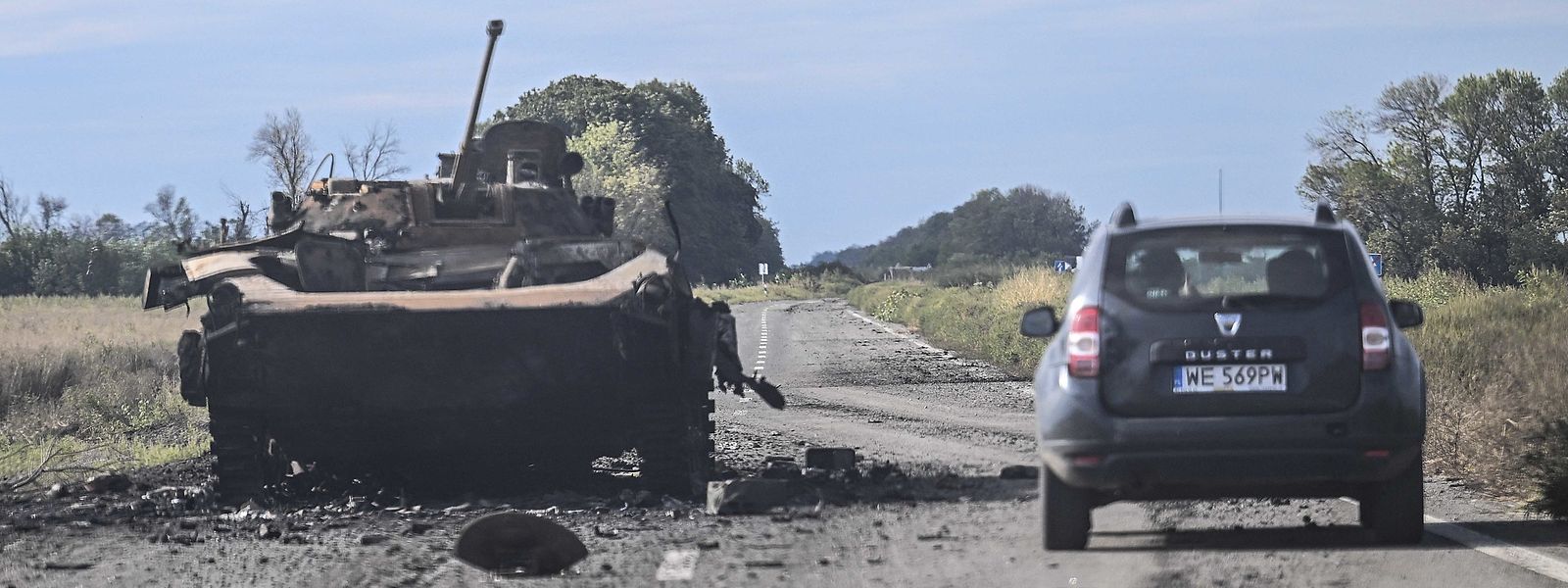 Um carro passa por um veículo blindado destruído em Balakliya, região de Kharkiv.