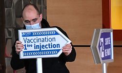 An employee at the Dunkirk Hospital Center sets-up signs to guide patients arriving to be administered with the Covid-19 vaccine on February 17, 2021. - Vaccination and screening have been stepped up in Dunkirk, where the spread of the variants has worried authorities with 2,400 doses of Moderna vaccines being sent urgently to the area. (Photo by DENIS CHARLET / AFP)