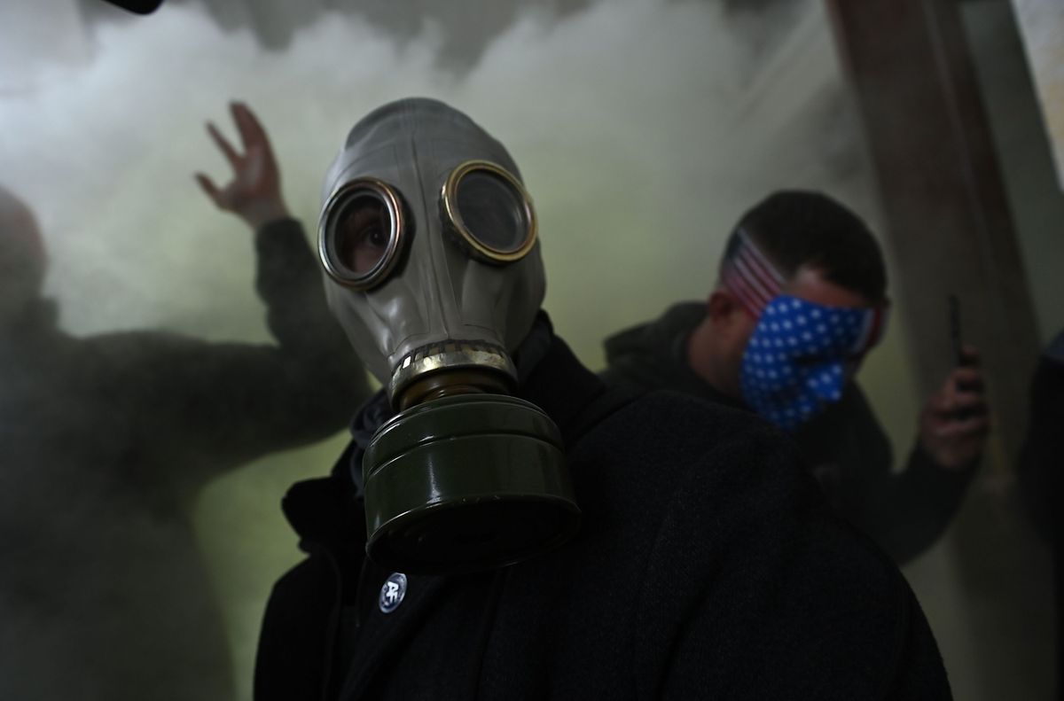 Ein Trump-Anhänger trägt eine Gasmaske in einer Wolke aus Tränengas.