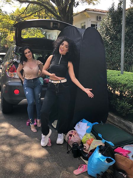 Fernanda Nunes (l.) und Lidya Gualano (r.) laden Klamotten aus einem Wagen und stellen sie neben ein Umkleidezelt im schicken Viertel Jardim Europa. 