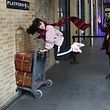 A Harry Potter fan poses for a photograph during a visit to Platform Nine and Three-Quarters at Kings Cross station in London, Britain, March 21, 2017. REUTERS/Neil Hall  SEARCH "HALL POTTER" FOR THIS STORY. SEARCH "WIDER IMAGE" FOR ALL STORIES.