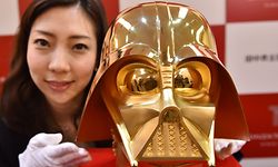 An employee of Japan's jeweler Tanaka Kikinzoku Jewelry displays a pure gold life size mask of Darth Vader, a character in the Star Wars, at their main shop in Ginza shopping district in Tokyo on April 25, 2017. 
The pure gold mask will go on sale on May 4 to commemorate the 40th anniversary of the movie. / AFP PHOTO / Kazuhiro NOGI