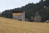 PRODUKTION - 23.02.2023, Bayern, Buching: "Skilift" ist an einer Hütte auf einer schneelosen Skipiste zu lesen. Angesichts der vielfach geringen Schneedecke in den Alpen und des regenarmen Februars droht laut Experten bald massive Trockenheit. (zu dpa: «Alarmierend wenig Schnee: Massive Trockenheit droht») Foto: Karl-Josef Hildenbrand/dpa +++ dpa-Bildfunk +++