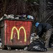 04.01.2022, Libanon, Beirut: Ein Junge wühlt in der Hamra-Straße in Beirut neben einem Müllcontainer mit dem Logo des US-Fastfood-Riesen McDonald's im Müll. Die libanesische Währung hat einen neuen Tiefststand gegenüber dem US-Dollar erreicht und wird mit rund 30.000 US-Dollar gehandelt. Damit hat sie mehr als 90 Prozent dessen verloren, was sie Ende 2019 wert war, als die libanesische Wirtschafts- und Finanzkrise ausbrach. Foto: Marwan Naamani/dpa +++ dpa-Bildfunk +++