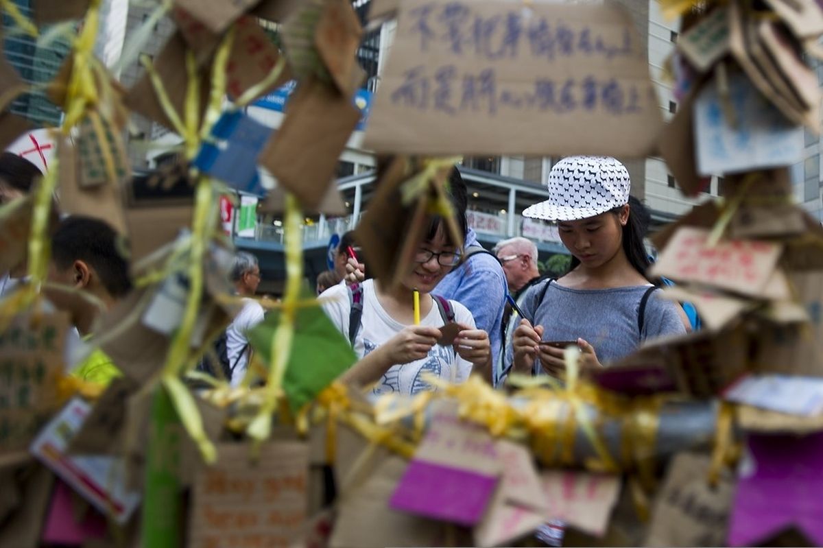 Two students write messages of in the Admiralty district of Hong Kong on October 2, 2014, as pro-democracy protesters remain gathered for the fifth day in a push for free elections of the city's leader. Tensions rose in Hong Kong on October 2 as the government urged demonstrators to "disperse peacefully as soon as possible" after police were seen unloading boxes of rubber bullets. AFP PHOTO / XAUME OLLEROS